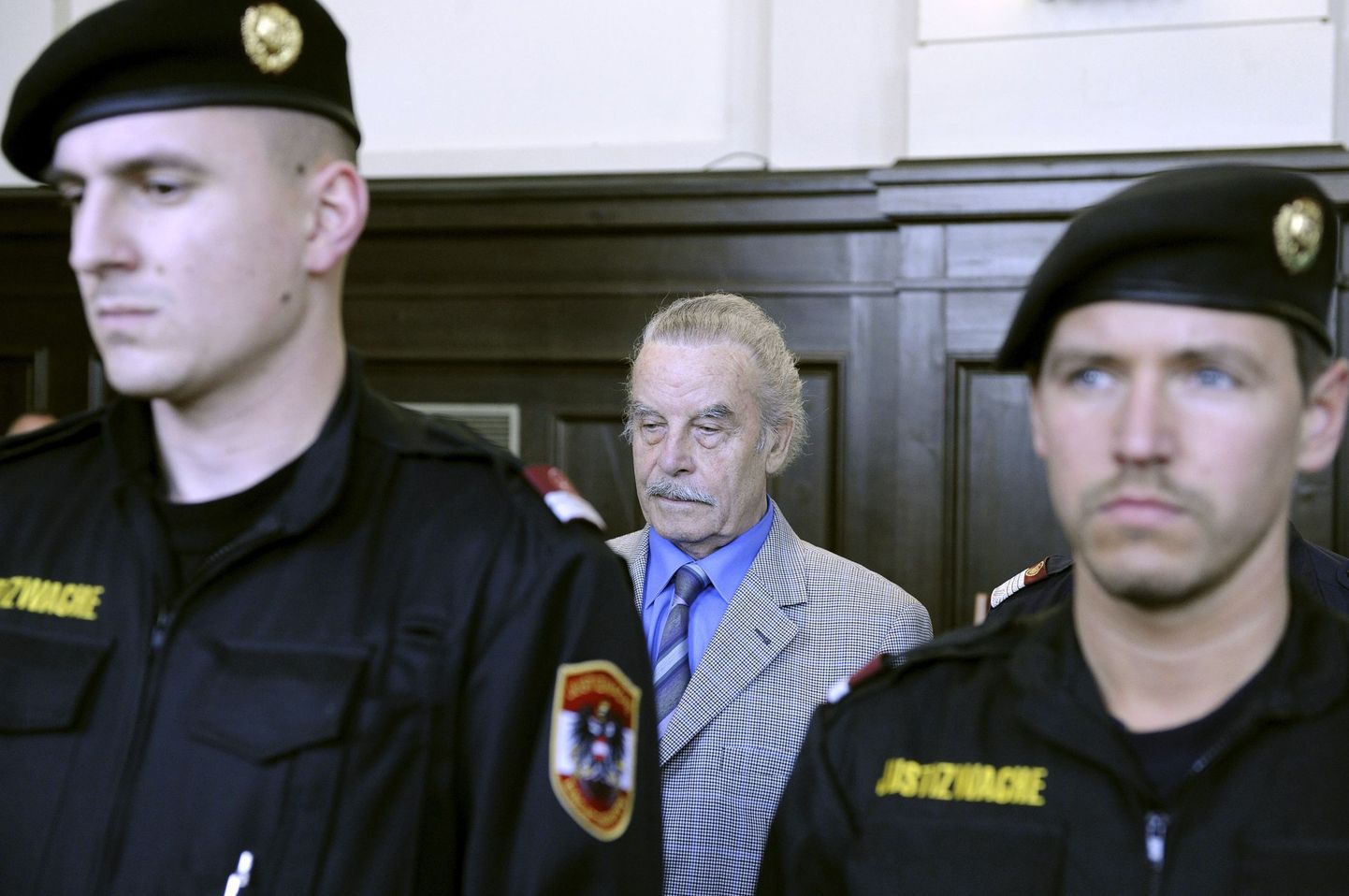 Josef Fritzl kohtusaalis. Ees seisavad politseinikud.