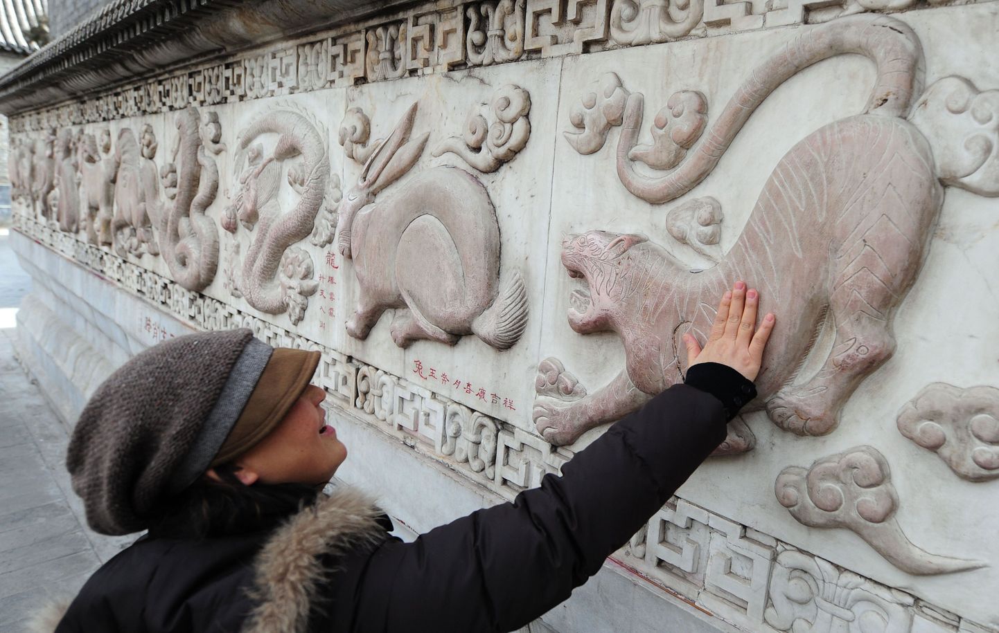 Pildil uuristab turist Hiina horoskoobimärke esindavaid loomi kujutavat reljeefi.