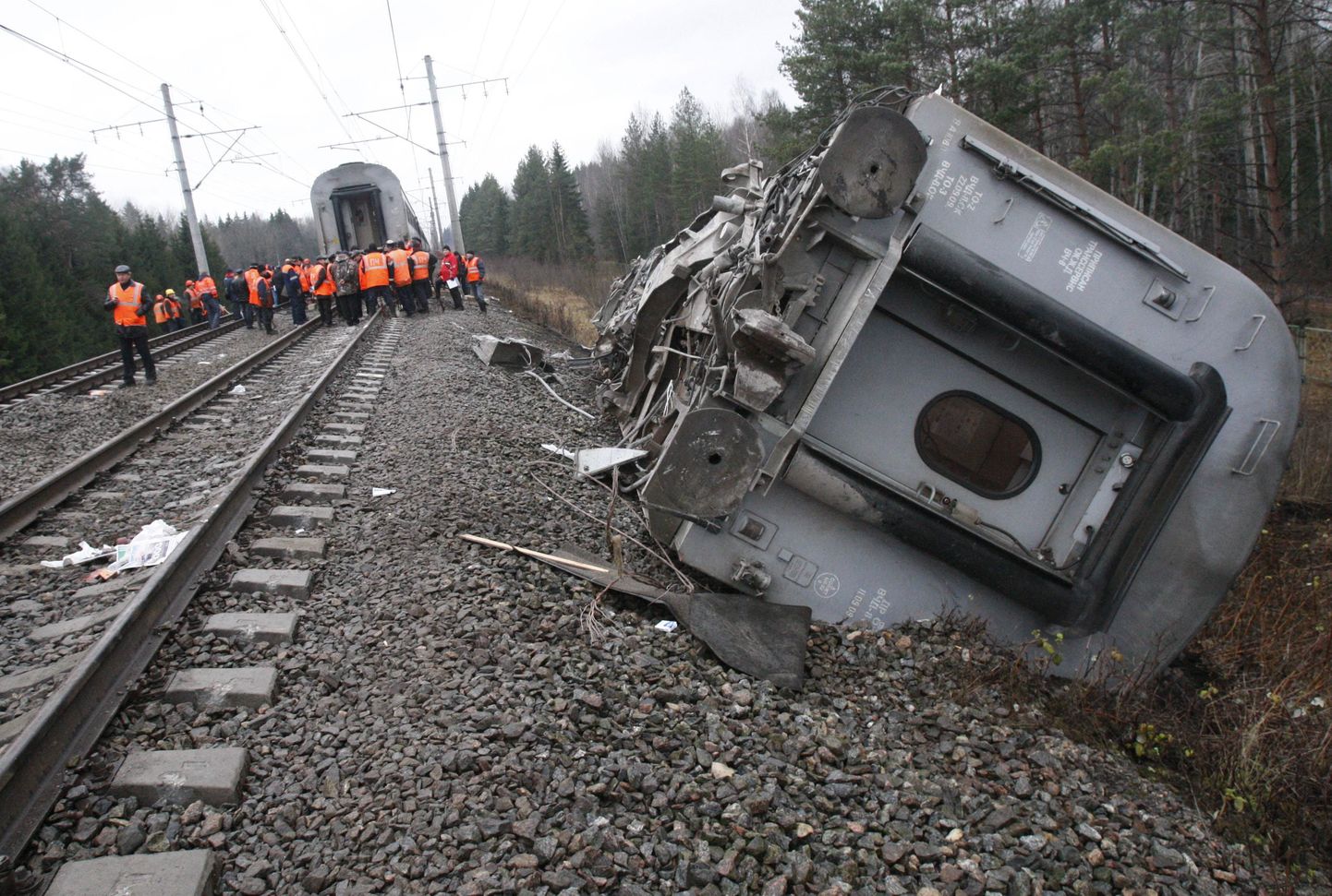 Railroad workers stand next to a damaged coach at the site of a train derailment near the town of Uglovka, some 400 km (250 miles) north-east of Moscow, Russia, Saturday, Nov. 28, 2009. An express train carrying hundreds of passengers from Moscow to St. Petersburg derailed, killing dozens of people and injuring scores of others in what may have been an act of sabotage, Russian officials said. (AP Photo/Ivan Sekretarev) / SCANPIX Code: 436
