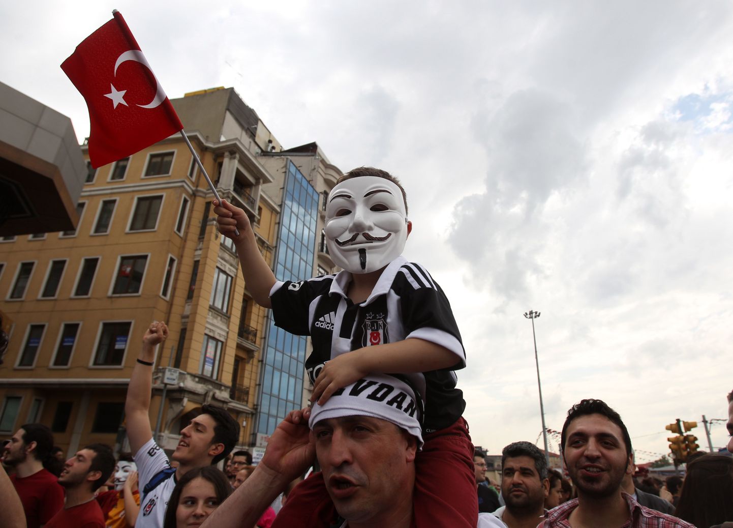 Mees kannab õlgadel maskiga poissi  Istanbulis Taskimi väljakul, kus rahvahulgad protesteerivad kolmandat päeva valitsuse plaanide vastu.