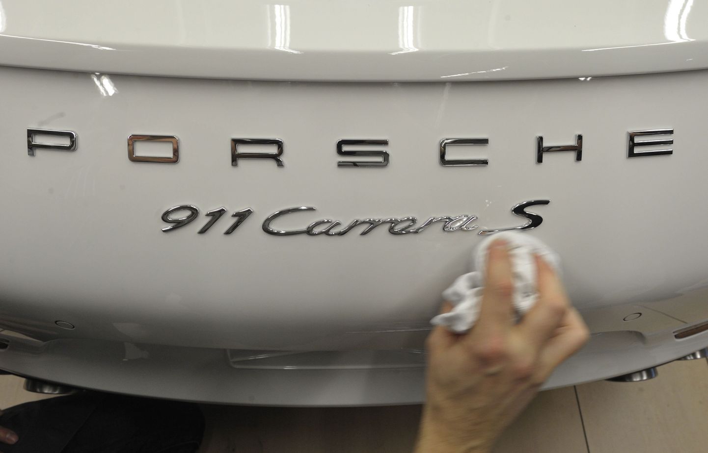 Porsche töötaja Stuttgarti tehases Porsche 911 sportautot puhastamas.