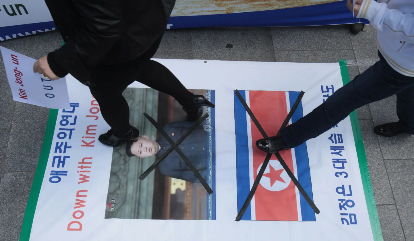 Põhja-Korea põgenikud astuvad Lõuna-Korea pealinnas Soulis üle plakati, millel on kujutatud Kim Jong-uni ja Põhja-Korea lippu.