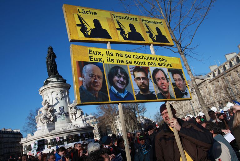 Mees plakatiga, millele kleebitud satiirilehe toimetuse hukkunud juhtide ja karikatuuride tegijate näod. FOTO: LOIC VENANCE/AFP/Scanpix