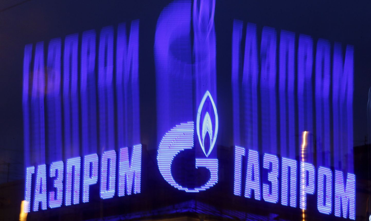 The company logo of Russian natural gas producer Gazprom is seen on an advertisement installed on the roof of a building in St. Petersburg, in this November 14, 2013 file photo. Russian gas producer Gazprom said on October 14, 2014, its first-half net profit was down to 450.58 billion roubles (6.92 billion pounds) from 582.7 billion roubles. Photo taken with long exposure.  REUTERS/Alexander Demianchuk/Files (RUSSIA - Tags: BUSINESS ENERGY)