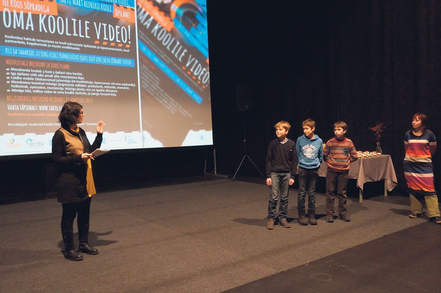 Mart Reiniku kooli poisid (vasakult) Robin Otter, Oliver Tummeleht ja Ott Allik kuulavad koolivideote esitlusel kriitikut Maria Murumaa-Mengelit. Paremal nurgas seisab poiste juhendaja Kristel Sibul.