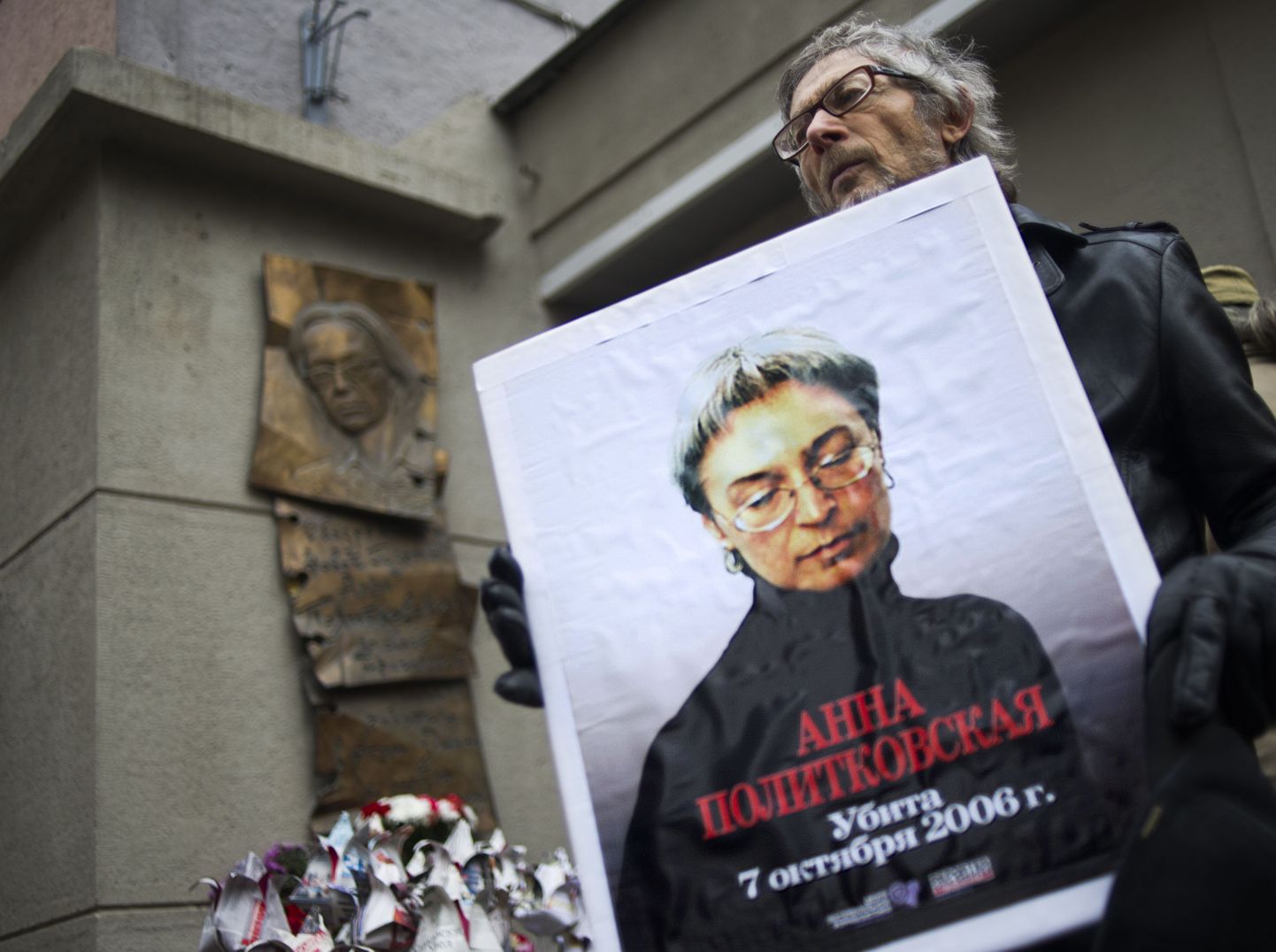 Житель Москвы держит портрет Анны Политковской в годовщину ее смерти.