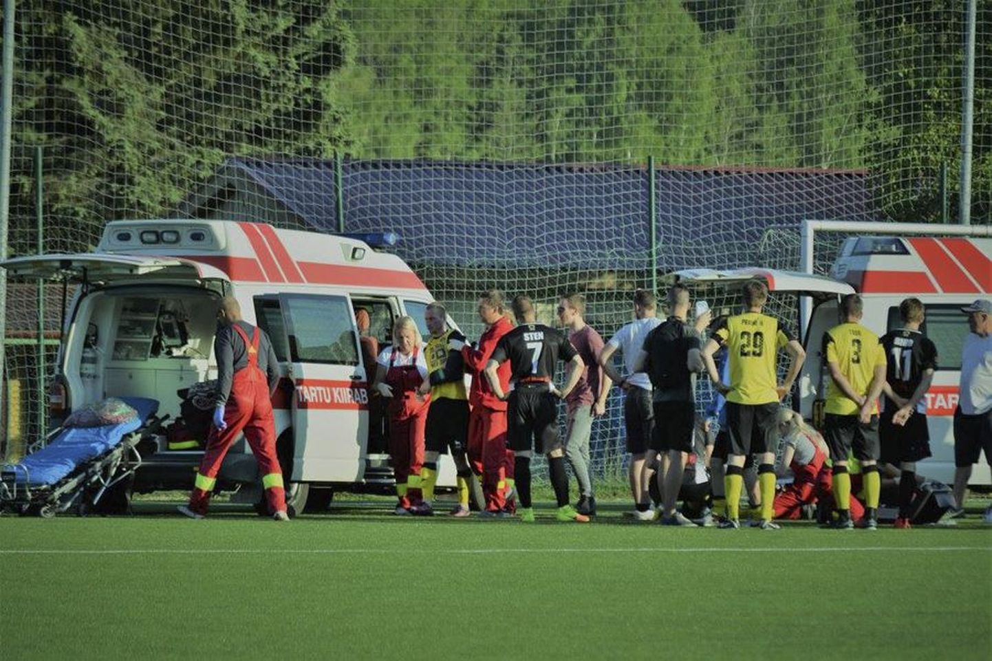 Fototabamus valusad pöörded võtnud jalgpallimängust. Vasakul talutatakse autosse rängalt viga saanud Kaido Kaljulat, paremal annavad arstid abi allergiahoo küüsi jäänud Sten Koobasele.