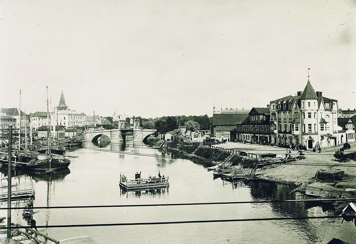20. sajandi algusest pärit vaade Emajõe paremale ja vasakule kaldale südalinna kohal. Lodjad, üleveopraam, hotell Jakor Uueturu ja Holmi tänava joonel.