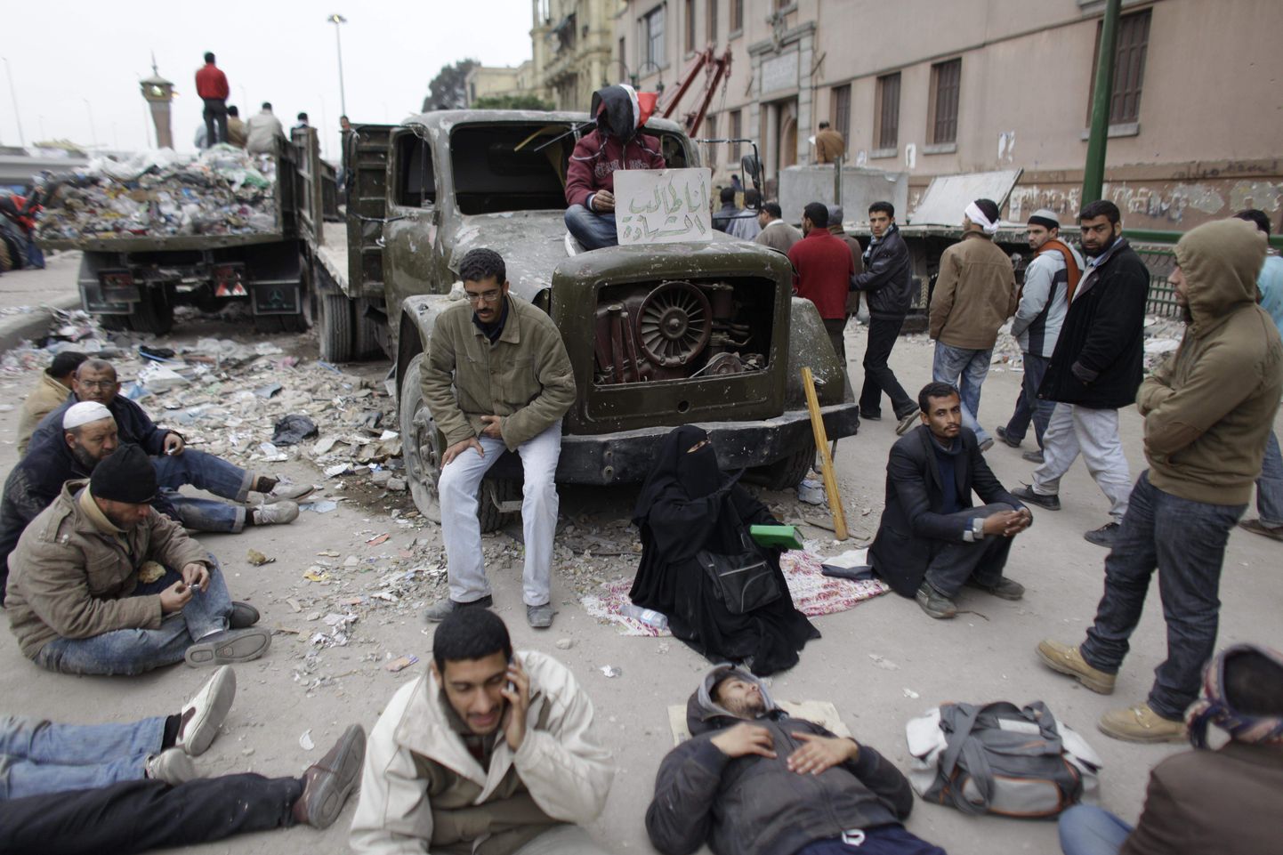 Valitsusvastased istuvad põlenud veoauto juures Kairos Tahriri väljakul.