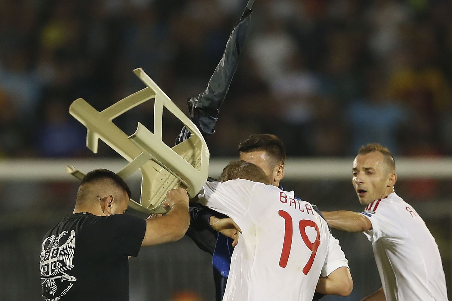 Сербский болельщик, выбежавший на поле, бьет табуреткой албанского футболиста.
