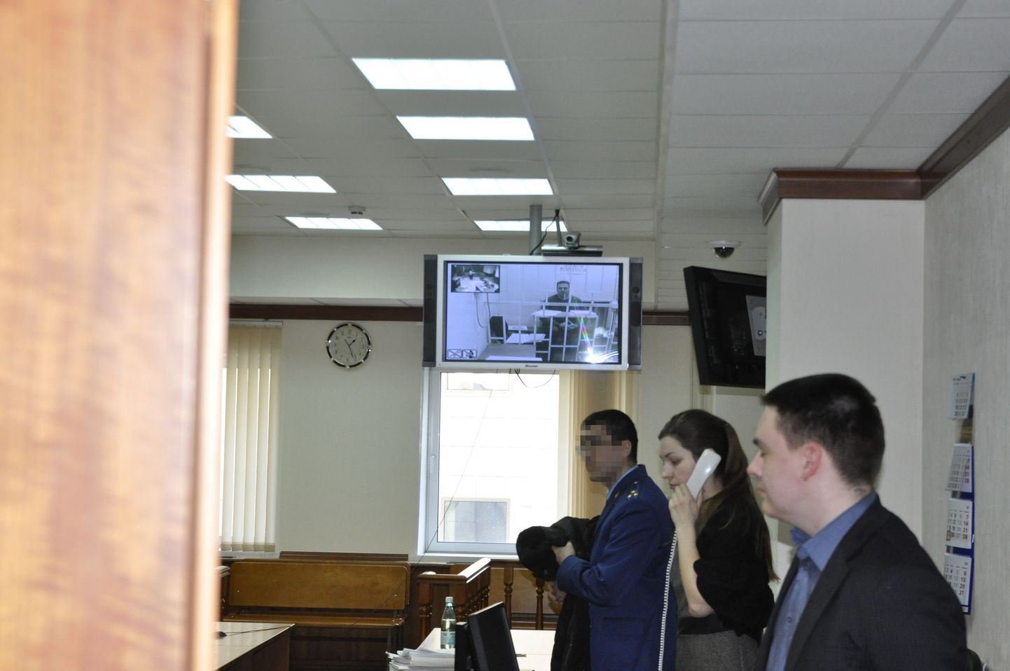 Postimehel õnnestus teha foto Moskva linnakohtu ukse vahelt enne vahi alt vabastamise arutamise algust. Raivo Susi on näha istumas saali tagaosas asuval tele-ekraanil.