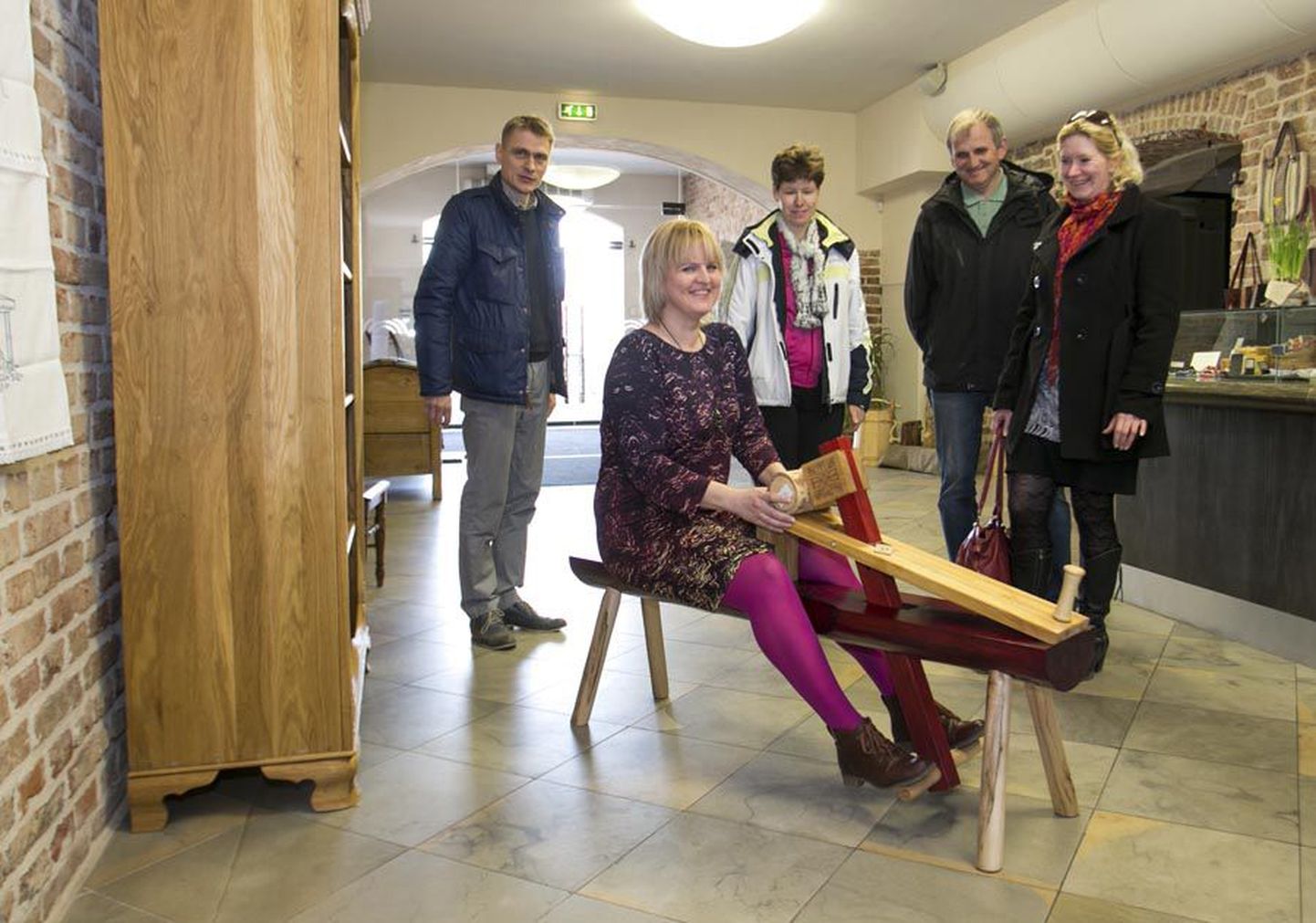 Palju küsimusi tekitab Janika Sepa tehtud salapärase otstarbega kaunis pink. Anneli Lilienthal näitab Lõuna-Eestist pärit külalistele, et sellel oli mugav puutööd teha.