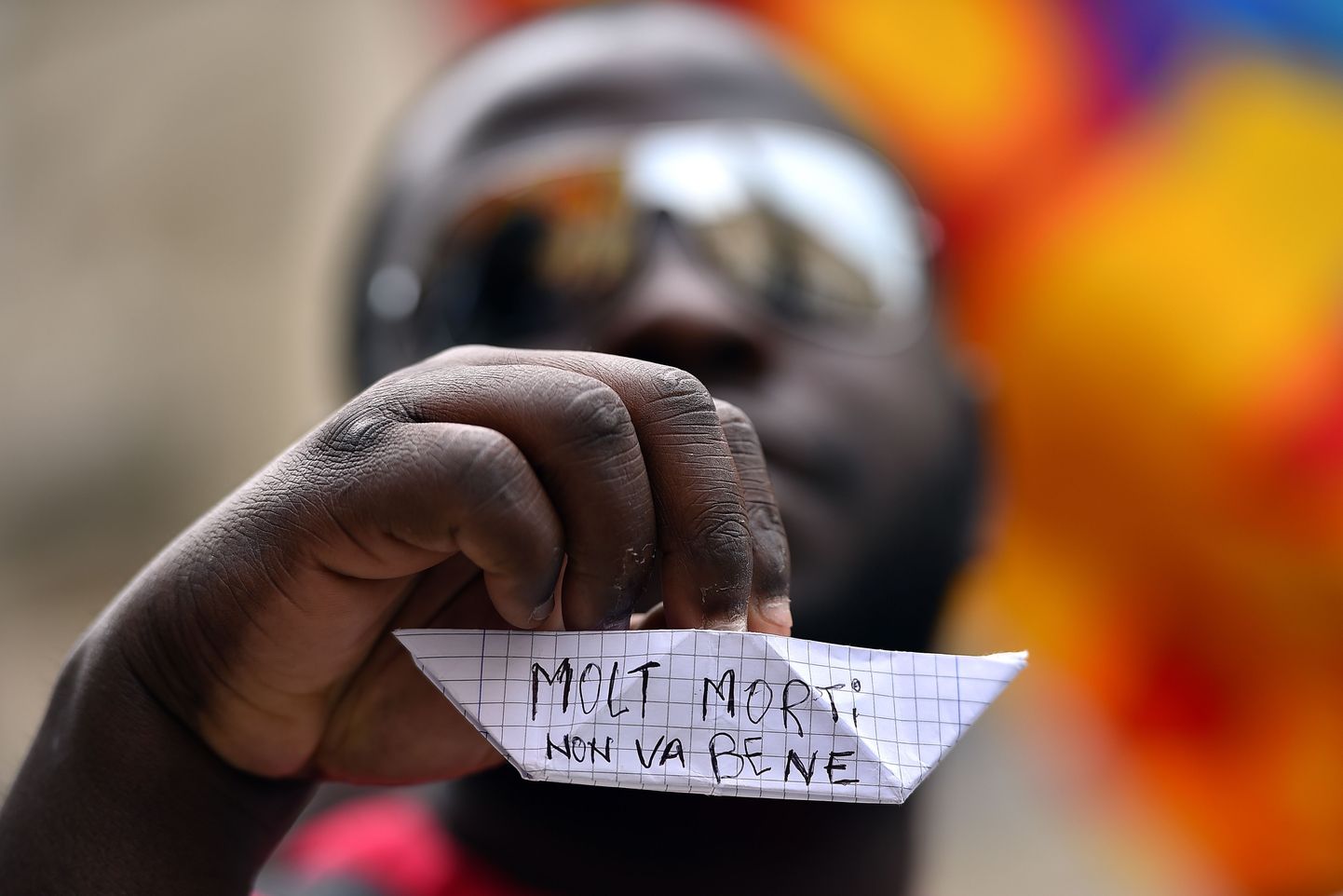 Varjupaigataotleja hoiab käes laevukest, mil kirjas  itaalia keeles «Liiga palju surmasid: see ei ole hea».