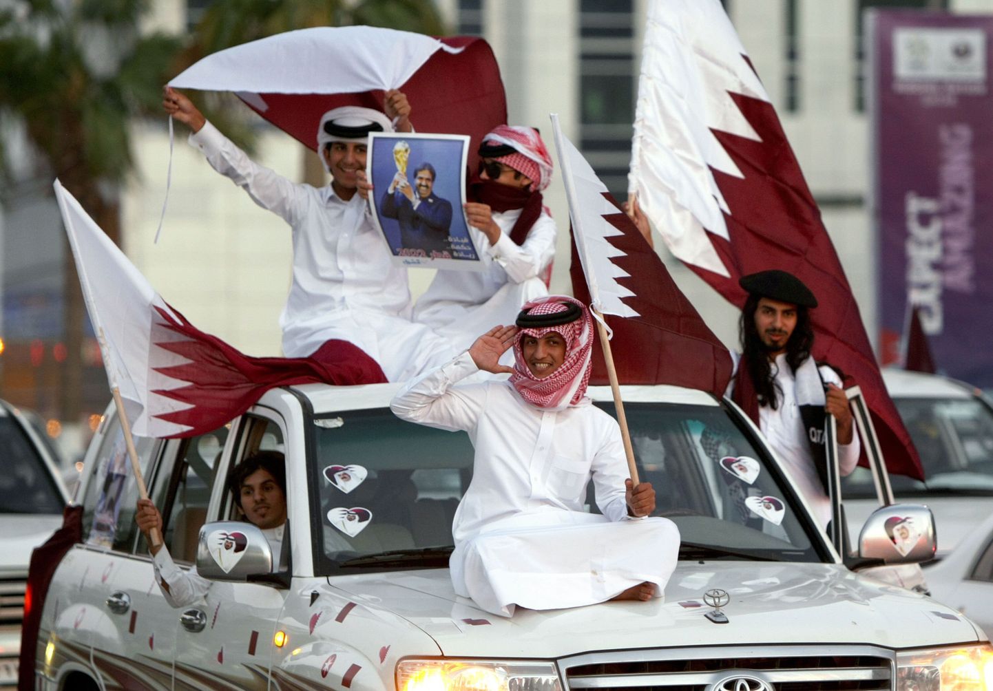 2010. aasta detsember – Katari elanikud tähistamas MMi korraldusõiguse saamist, käes pilt toona võimul olnud emiirist.