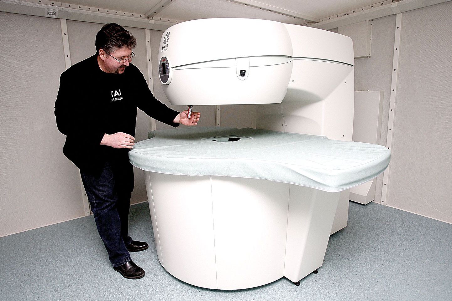Eesti Maaülikooli loomakliiniku juhataja Kalmer Kalmus näitab taskunoa abil tomograafi püsimagneti tugevust.
