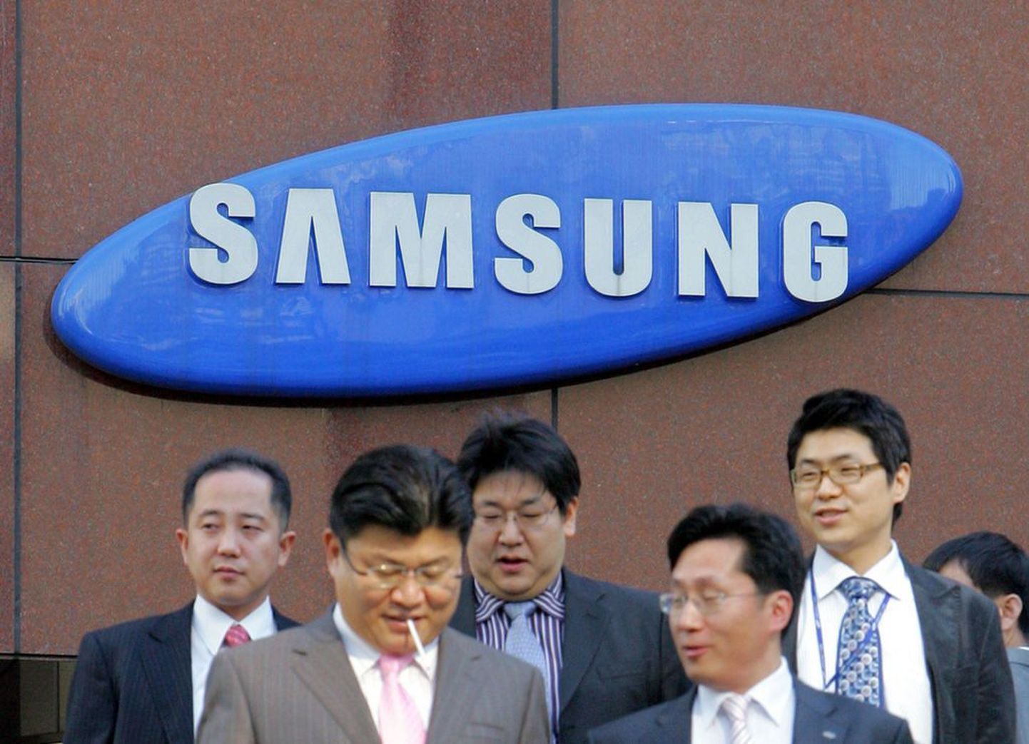 Lõuna-Korea ärimehed Samsung grupi logo ees.