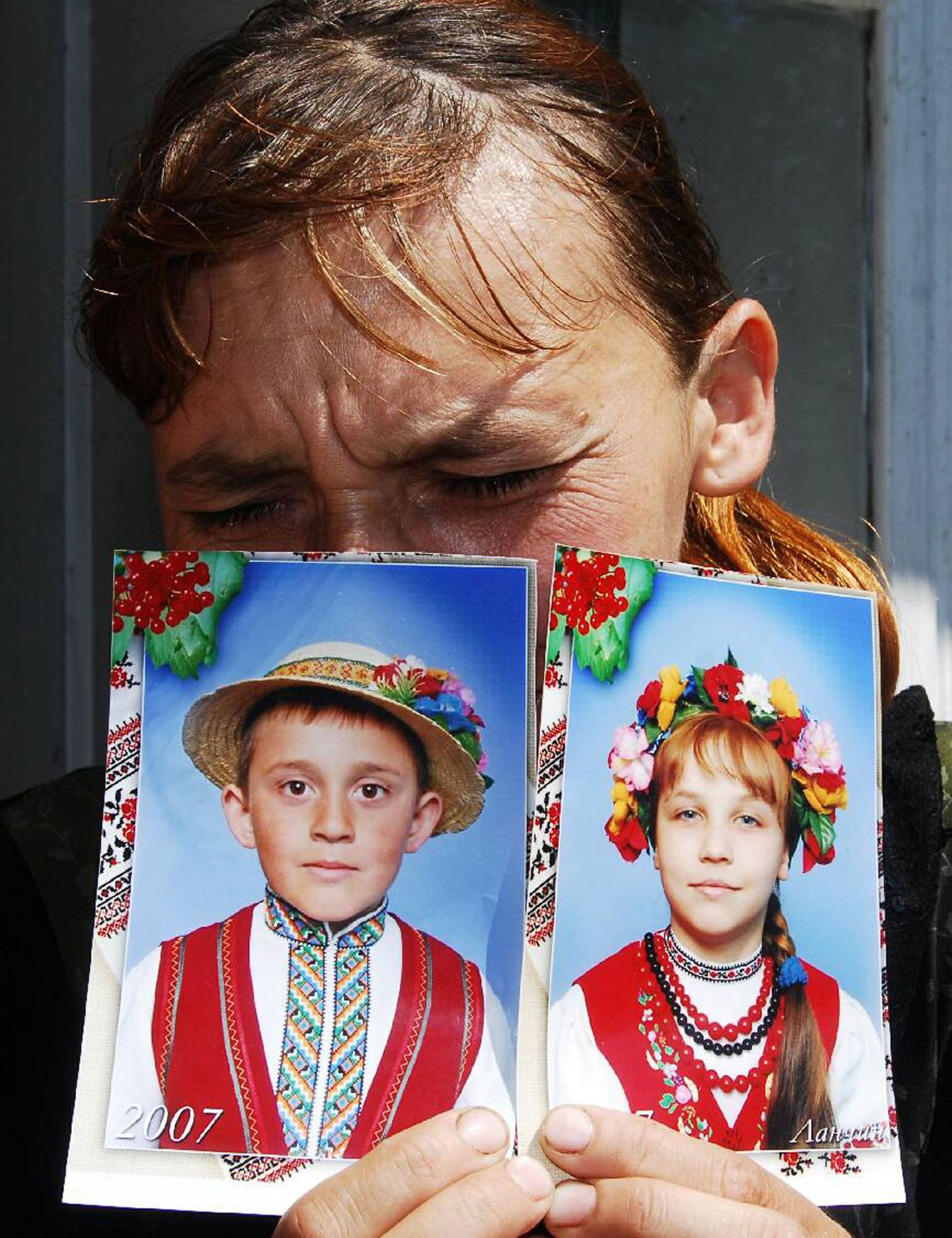 Ukrainlanna näitamas oma kahe lapse fotosid, kes hukkusid juulilõpus riiki tabanud üleujutuste käigus.
