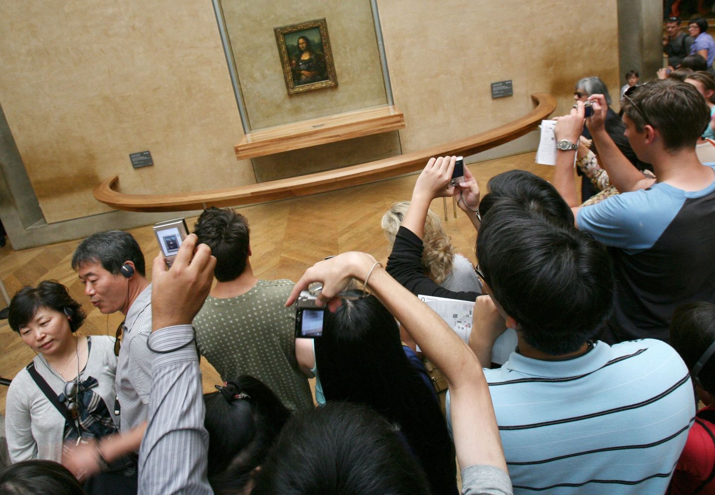 Turistid Mona Lisa maali pildistamas.