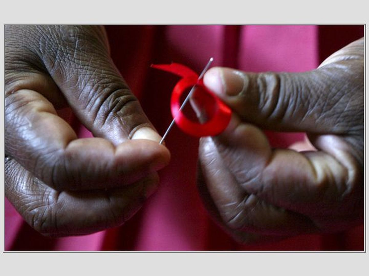 Keenia naine valmistamas AIDS-i vastu võitlemise sümbolina tuttavat punast paela
