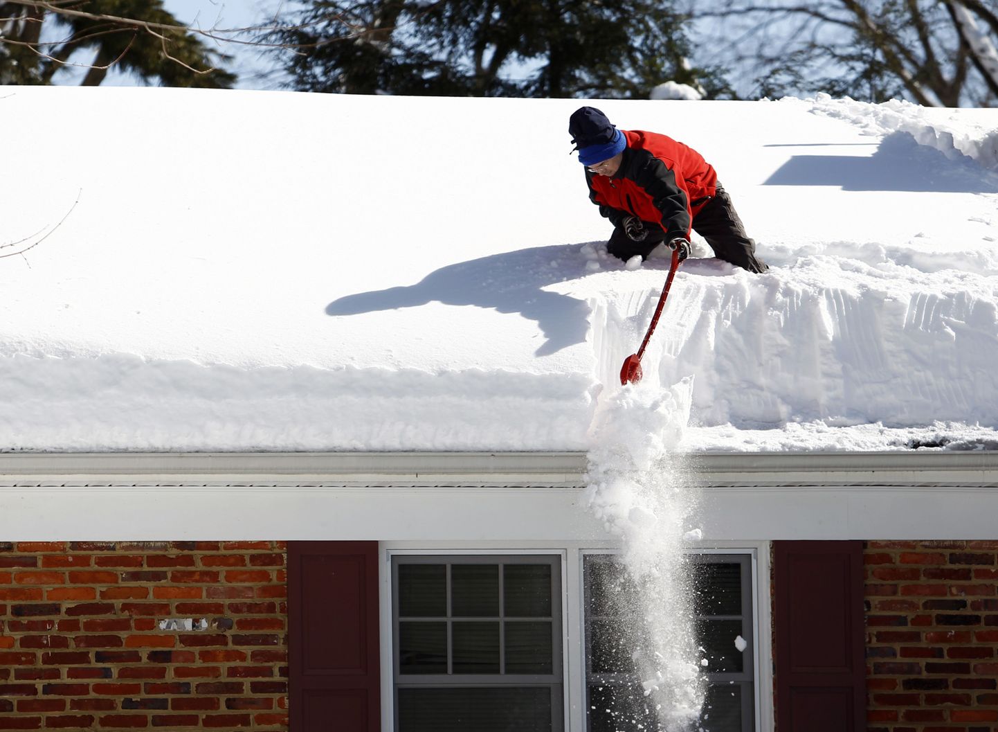 Mees lükkab oma maja katuselt lund alla.