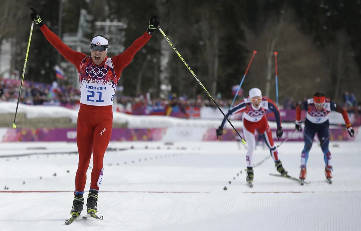 Dario Cologna on tõstnud võidukalt käed. Samas heitlevad Martin Johnsrud Sundby ja Maksim Võlegžanin (paremal) pronksi eest. Sundby on selgelt venelasele ette sõitnud.
