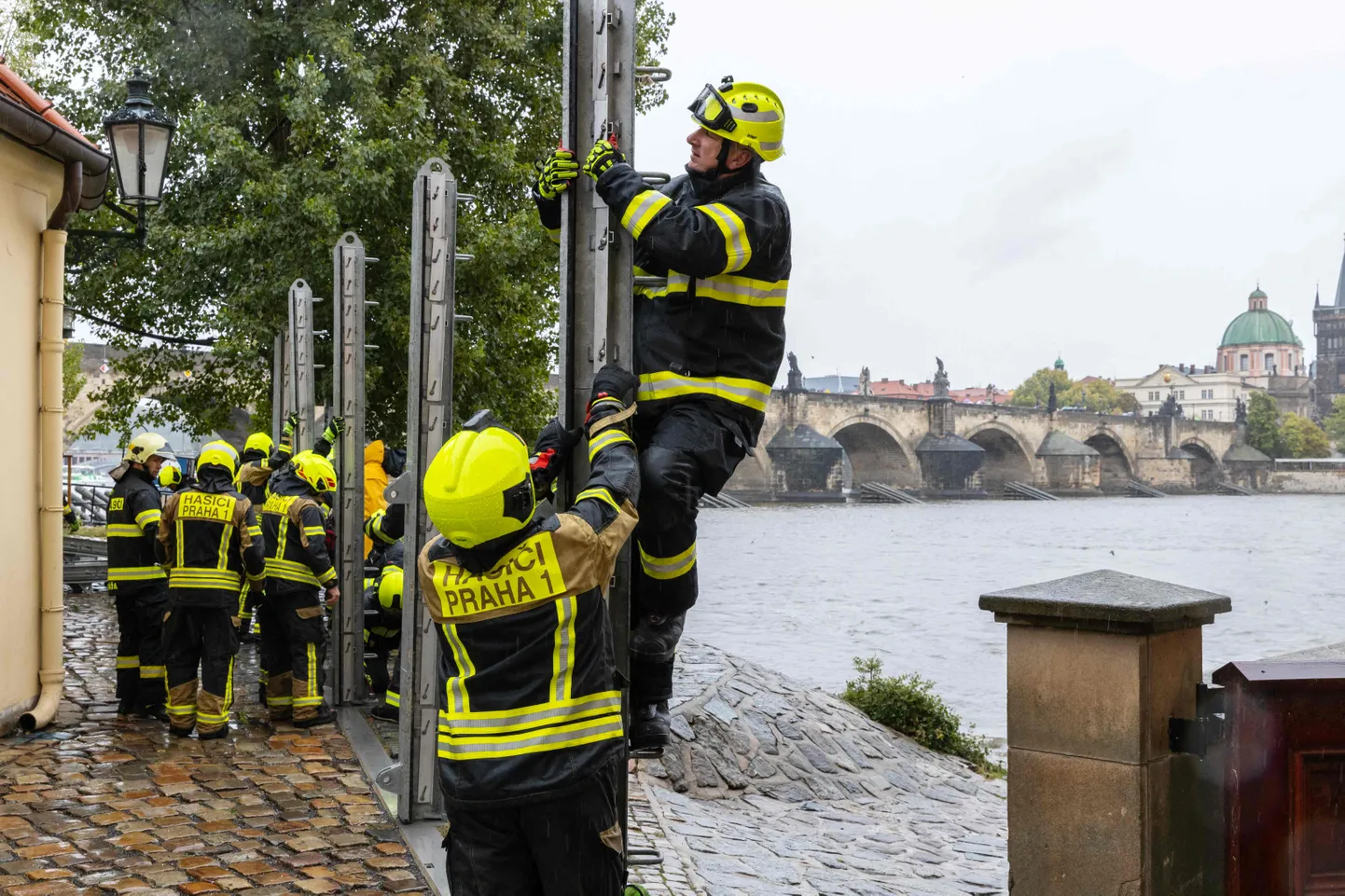 Ugunsdzēsēji būvē pretplūdu barjeras Vlatvas upes kreisajā krastā, netālu no Kārļa tilta Prāgā 2024. gada 13. septembrī