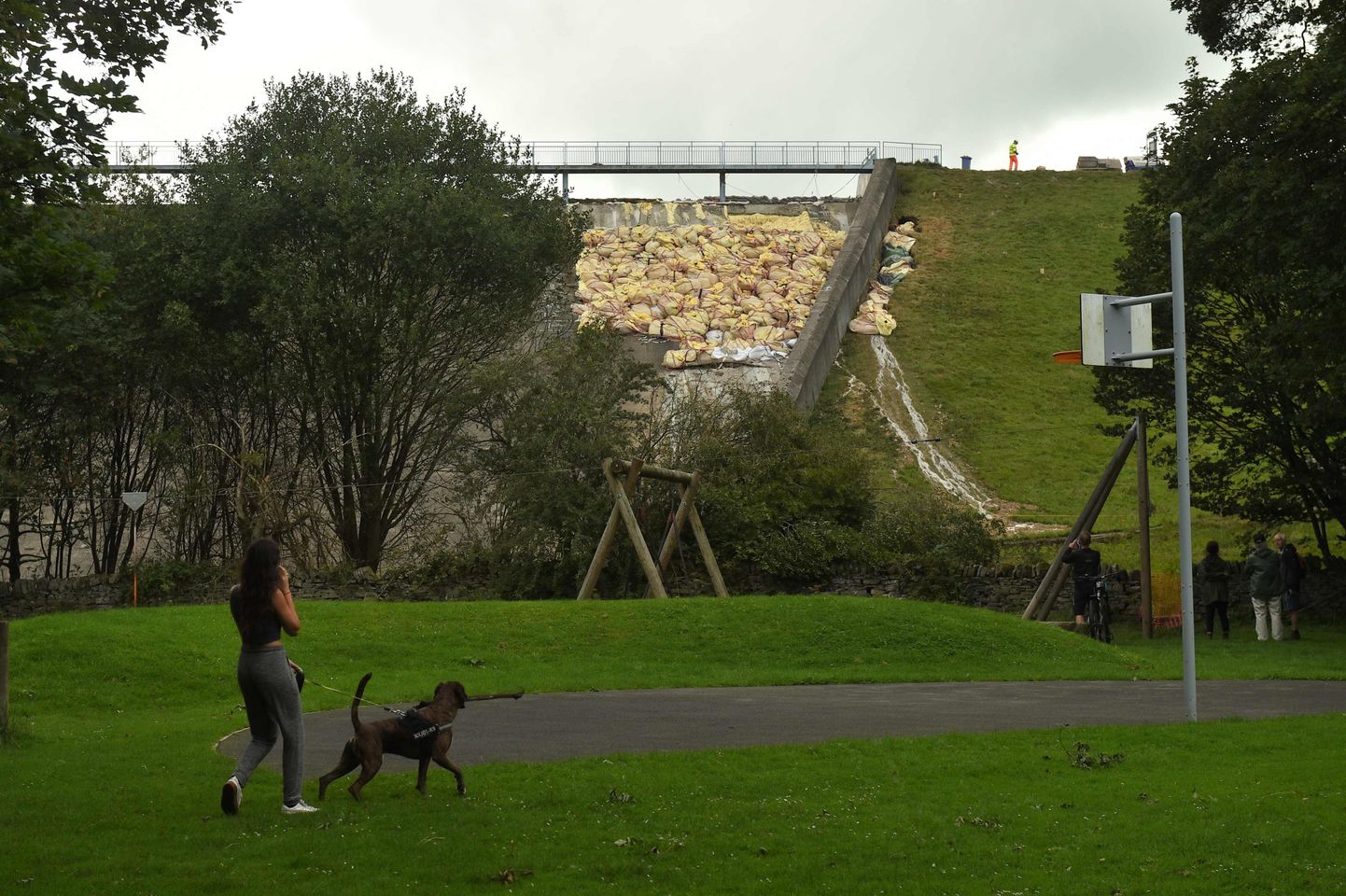 Veilībridžas iedzīvotāja pastaigājas netālu no bojātā dambja.