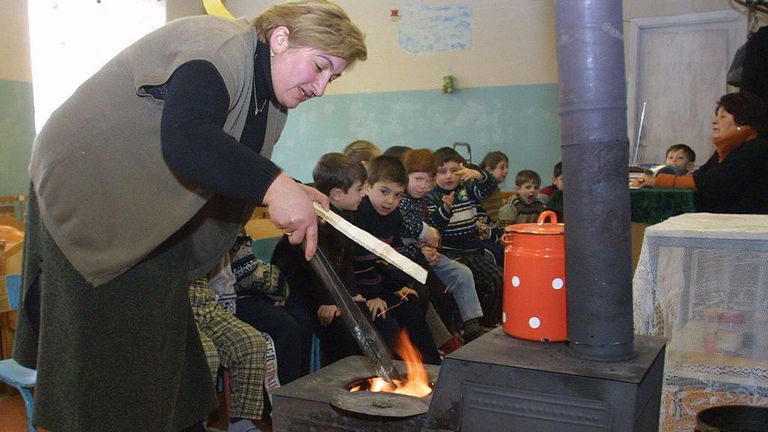 Женщина разжигает печку в детском саду.