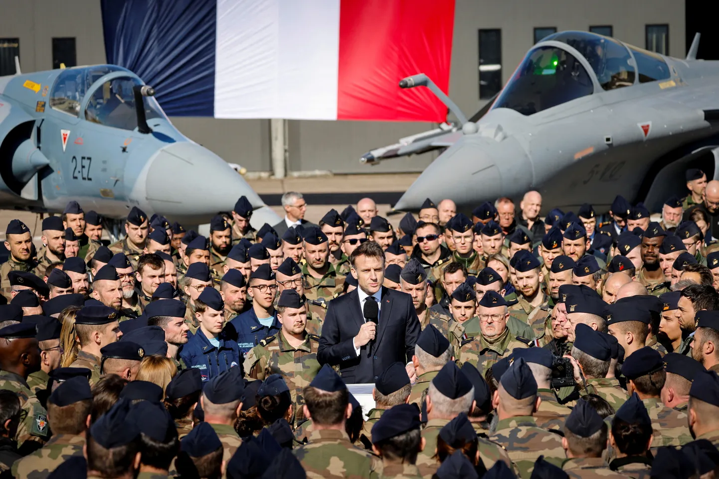 Prantsuse president Emmanuel Macron visiidil Luxeuil-Saint Sauveuri baasis, mis saab 1,5 miljardi eurose uuenduskuuri tuumapommitajate võõrustamiseks. Taustal hävituslennukid Dassault Rafale ja Dassault Mirage 2000. 18. märts 2025.