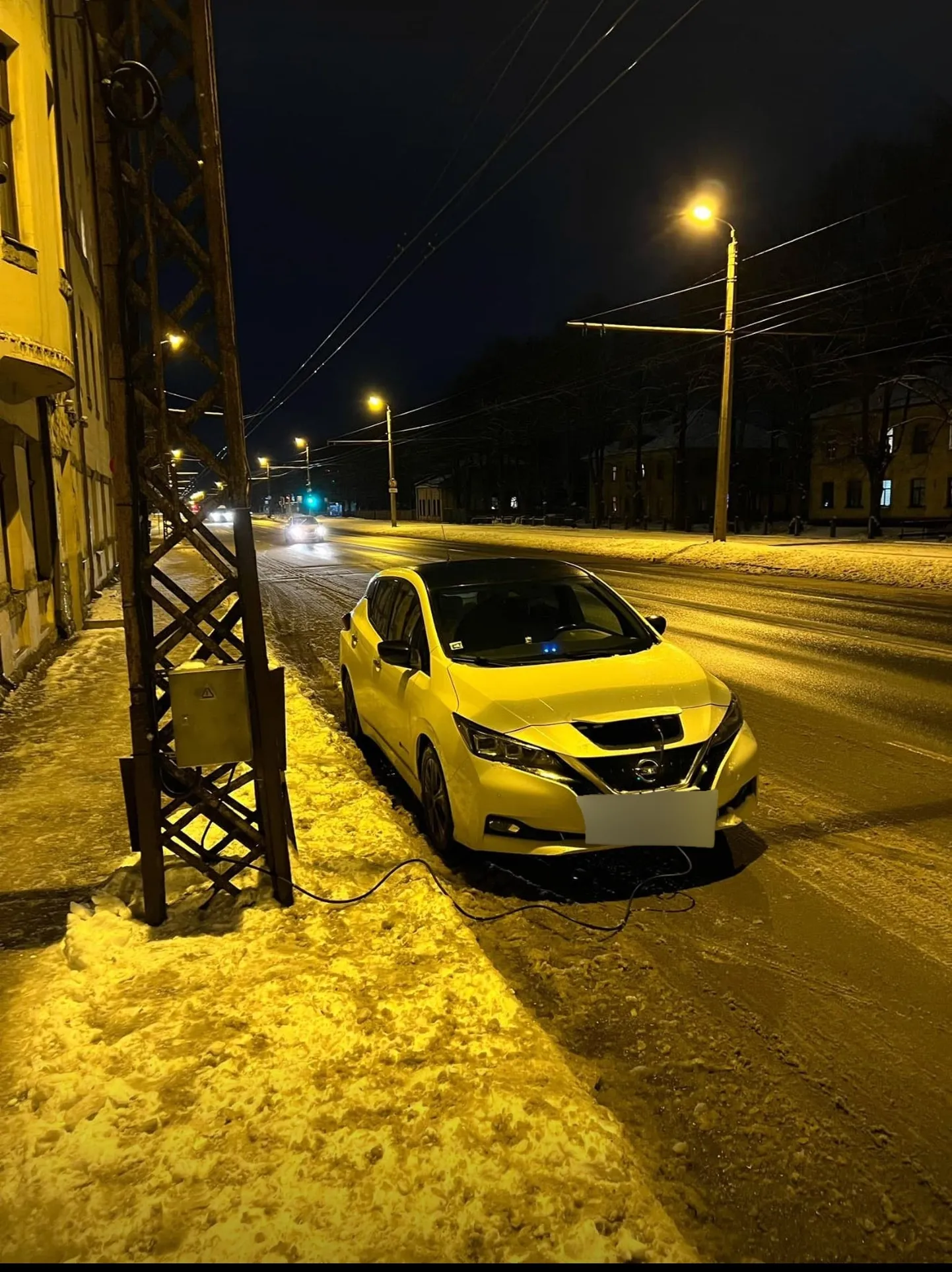 Электромобиль на зарядке у столба
