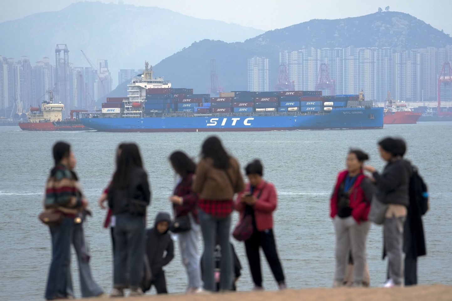 Konteinerlaev möödumas Xiamenis merevaadet nautivatest turistidest 26. detsembril 2023.
