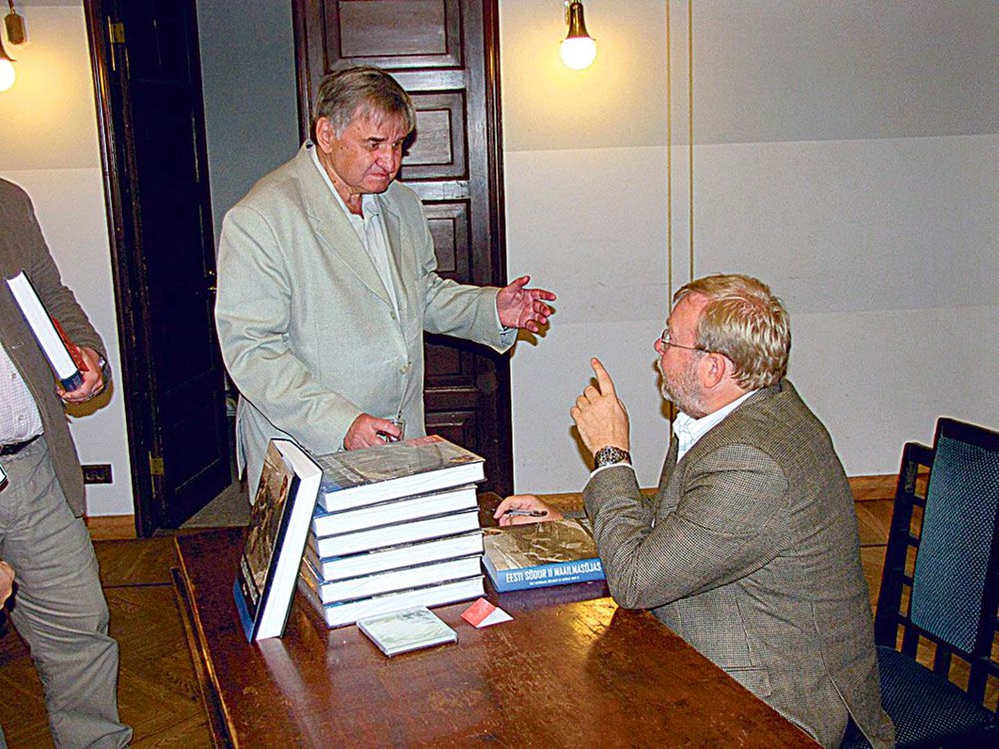 Linnart Mäll võtab raamatu autorilt Mart Laarilt autogrammi.