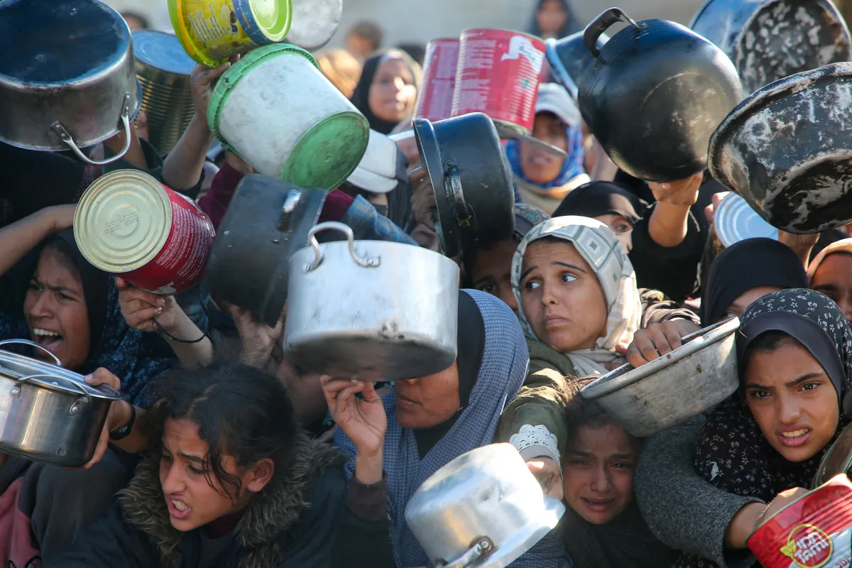 Palestinians gather to receive food cooked by a charity kitchen, amid a hunger crisis, as the Israel-Hamas conflict continues, in Khan Younis in the southern Gaza Strip, January 2, 2025.