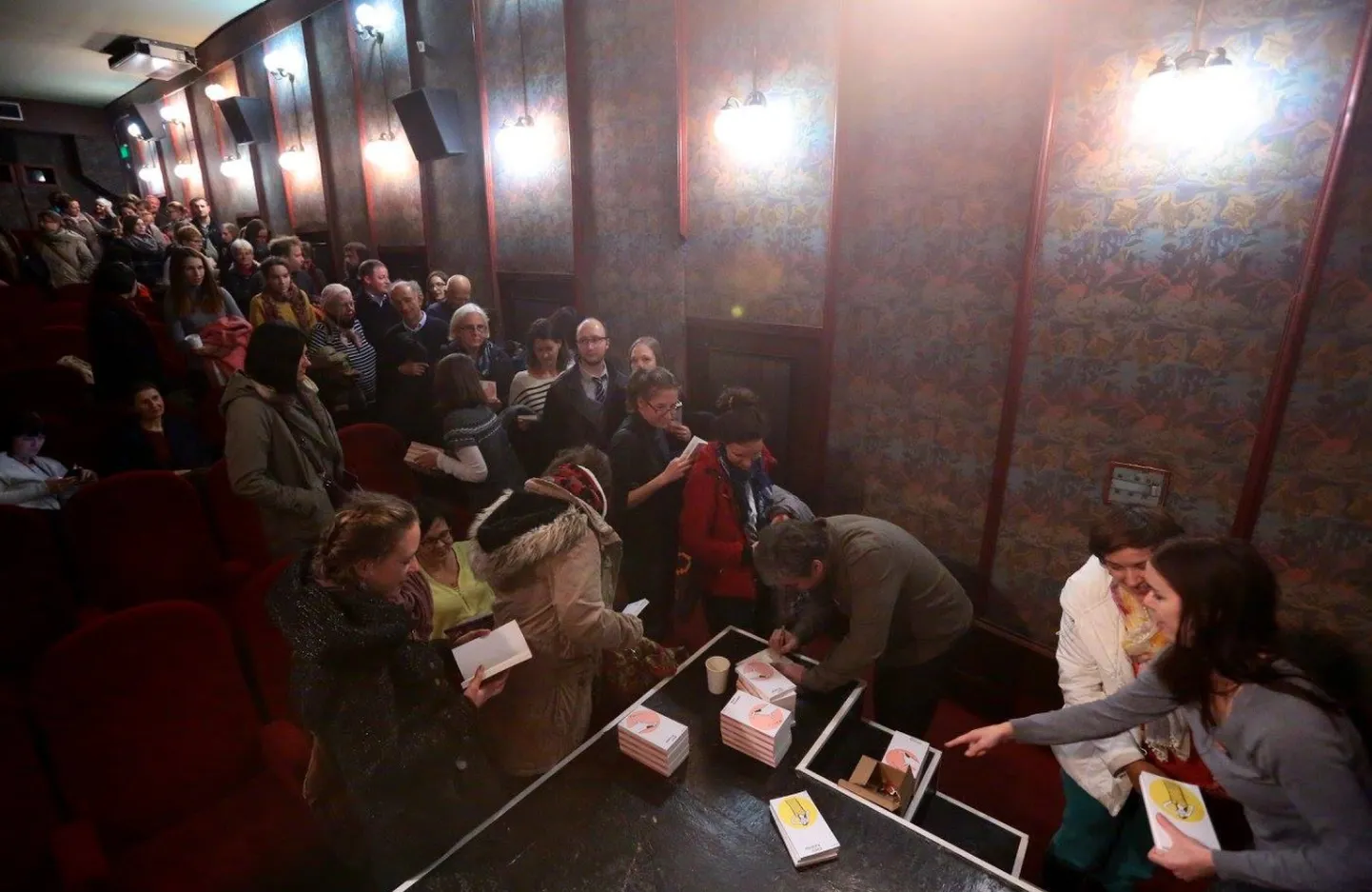 Mart Kivastik on ühe raamatu kohal kummargil ja kirjutab autogrammi. Lugejad ootavad kannatlikult järjekorras.