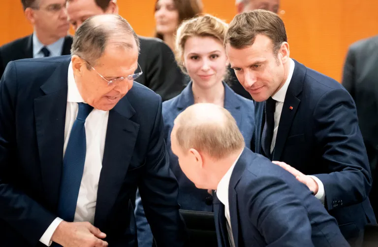 Сергей Лавров наблюдает, как президент Франции Эмманюэль Макрон помогает Путину переместиться из вертикального положения немного пониже.