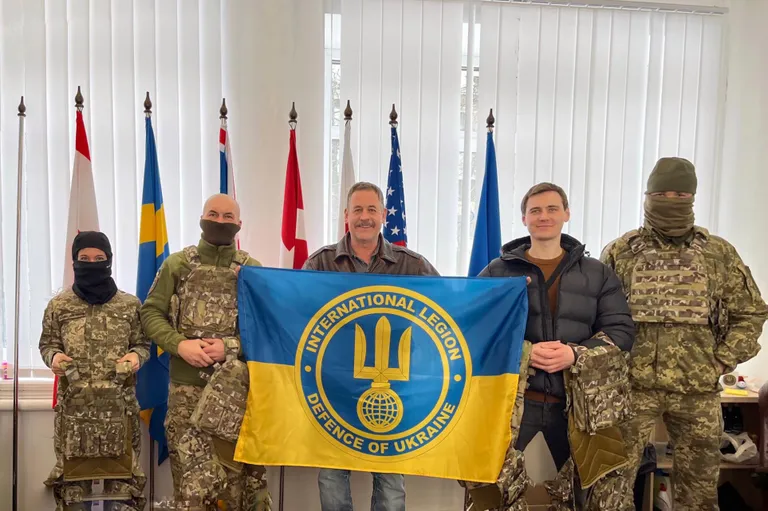 Бойцы «Иностранного легиона» Украины позирую с флагом легиона, 21 февраля 2023 года.
