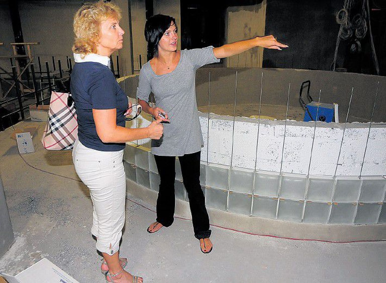 Atlantise juhataja Olga Aasav (vasakul) ja programmijuht Mai-Liis Sipria näitavad arhitekti-disaineri koostöös kujundatud ringikujulist klaasplokkidest baariletti, mis hakkab piduliste silme all värvi muutma.