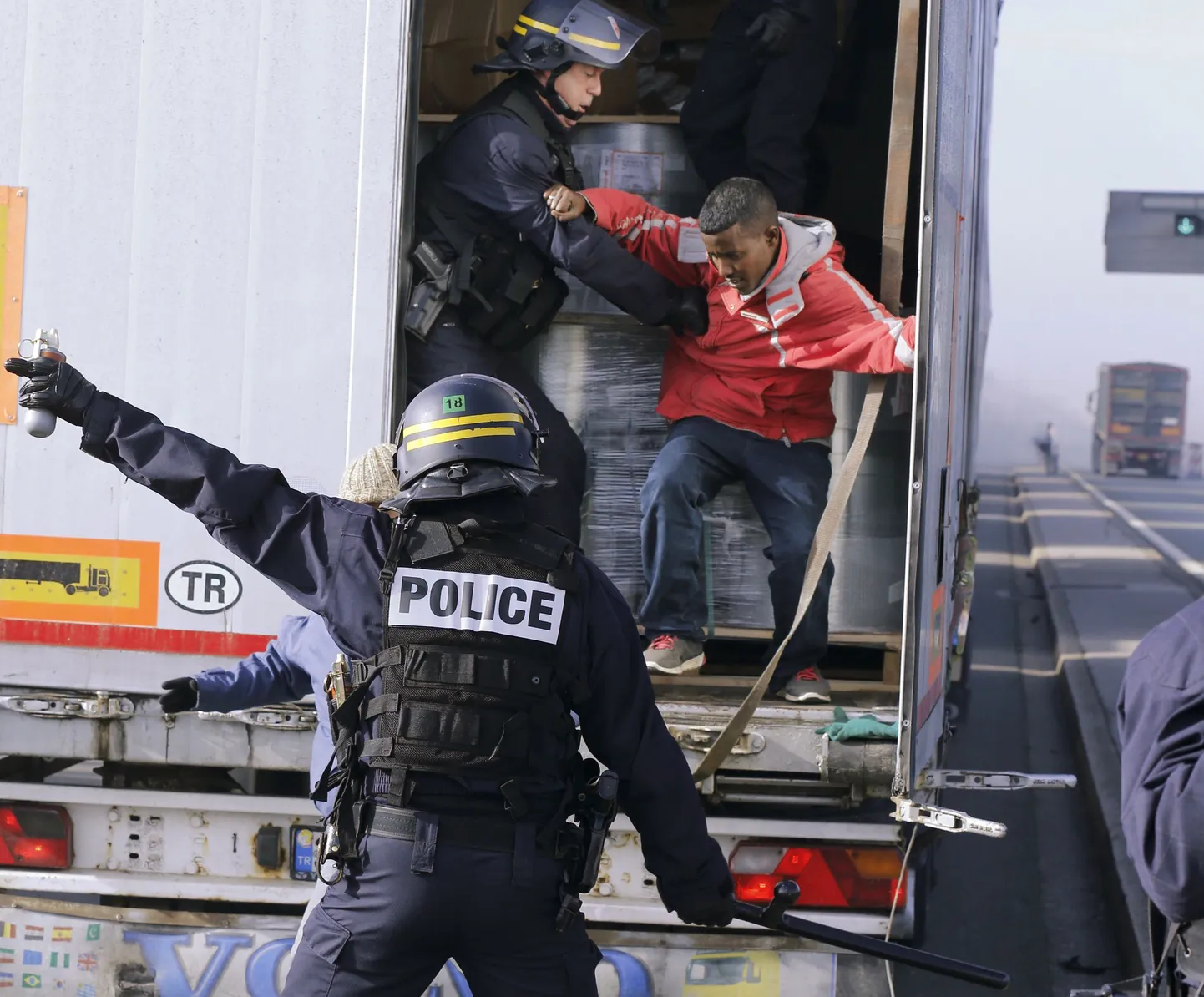Prantsuse märulipolitsei tõstab Calais' sadamas ühest veokist välja seal end varjanud migranti.