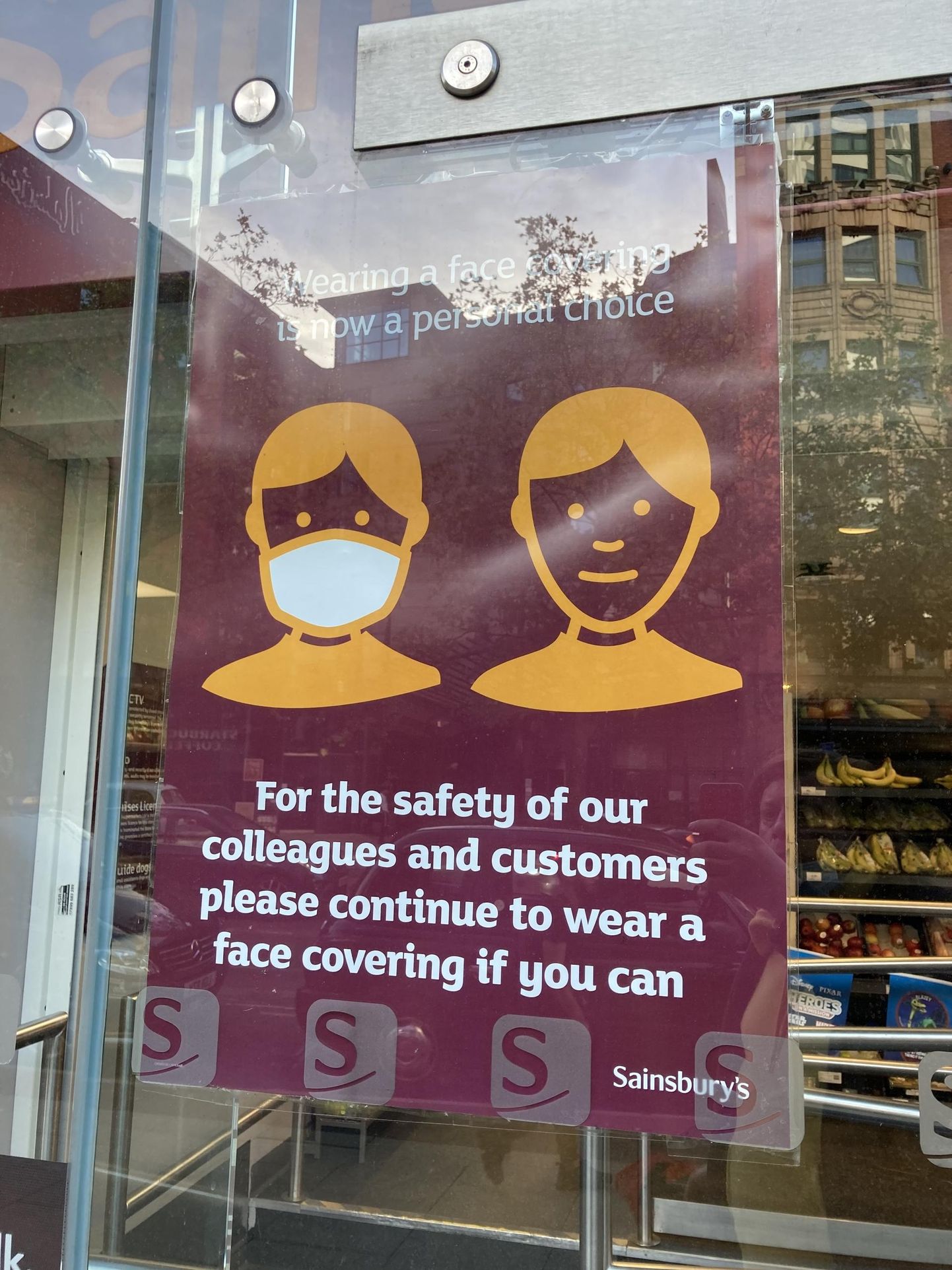 Plakat Londoni poeaknal kutsub üles kandma näokatet. Poodides seda üleskutset väga kuulda ei võeta, kuid rongides on maskiga ehk pooled inimesed.