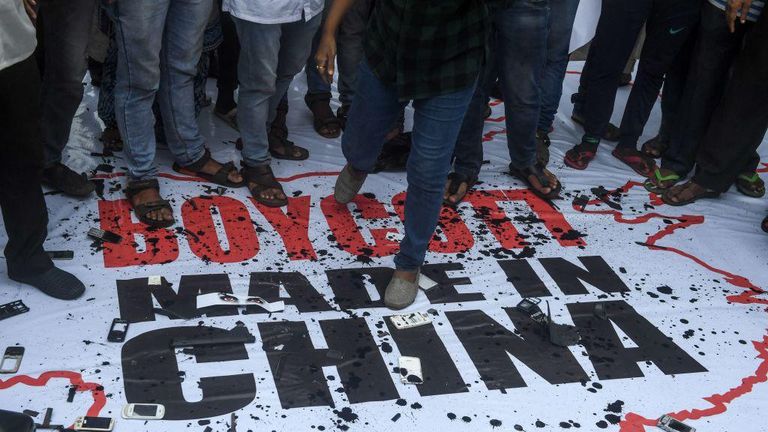 Люди топчут плакат, призывающий бойкотировать товары из Китая