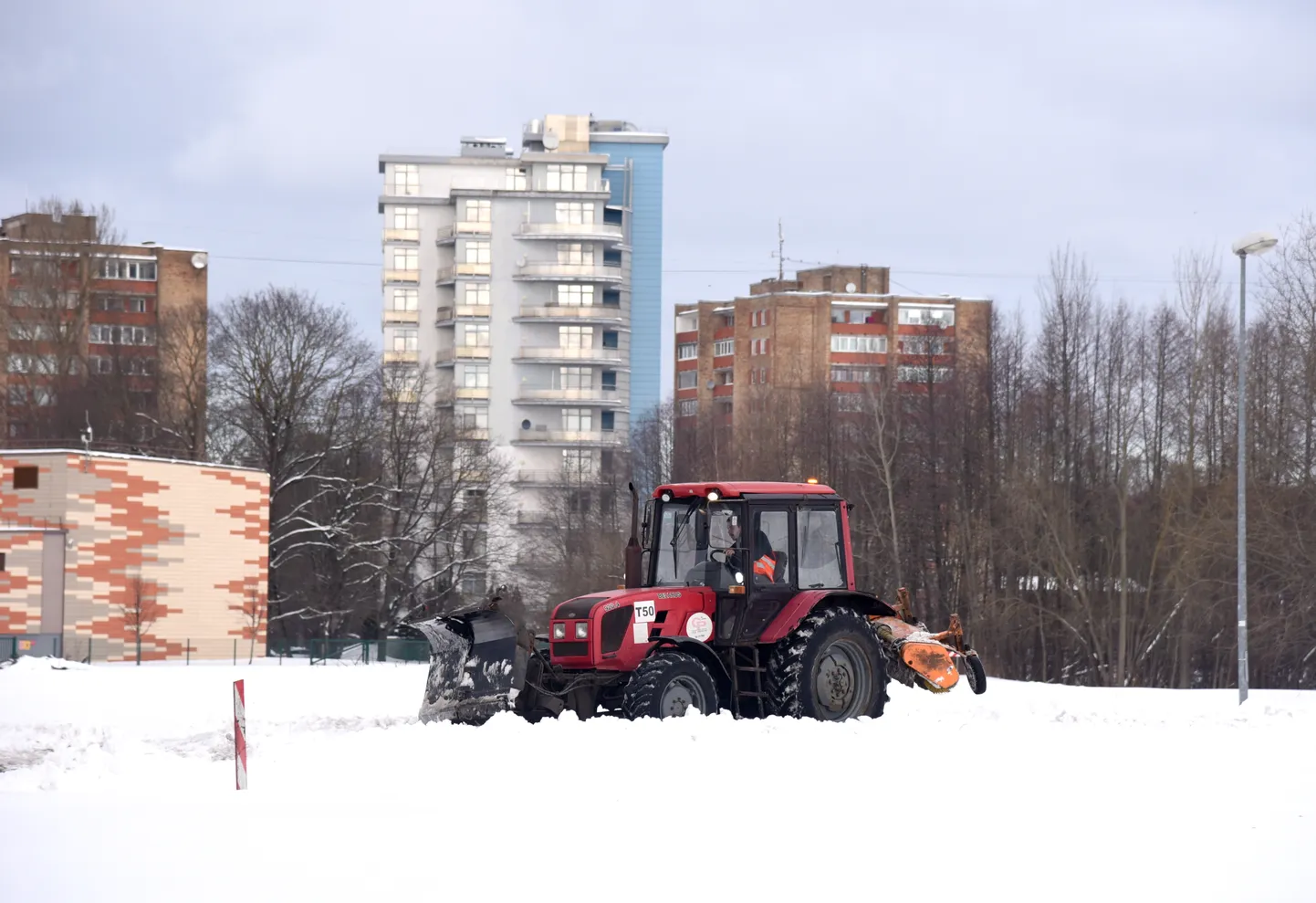 Ar traktoru tiek tīrītas piesnigušās ielas Čiekurkalnā.