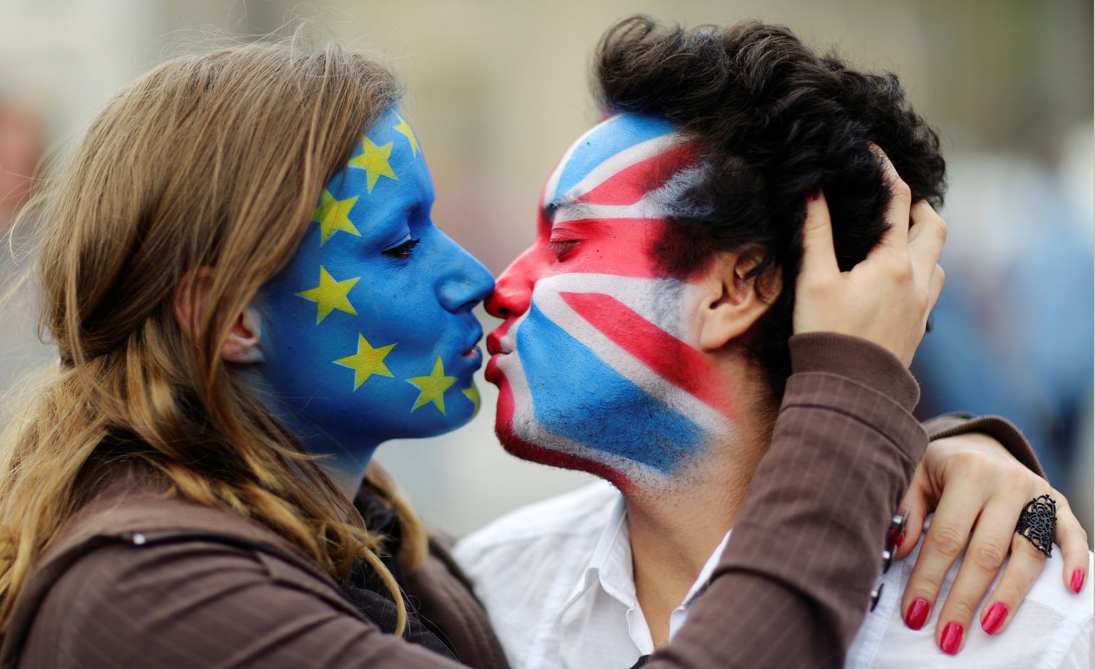 EL lipuvärvidega naine suudlemas Briti lipuvärvidega meest.