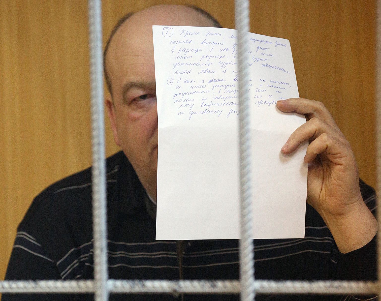 Aleksandr Reimer varjas Moskva kohtusaalis oma nägu paberilehega.