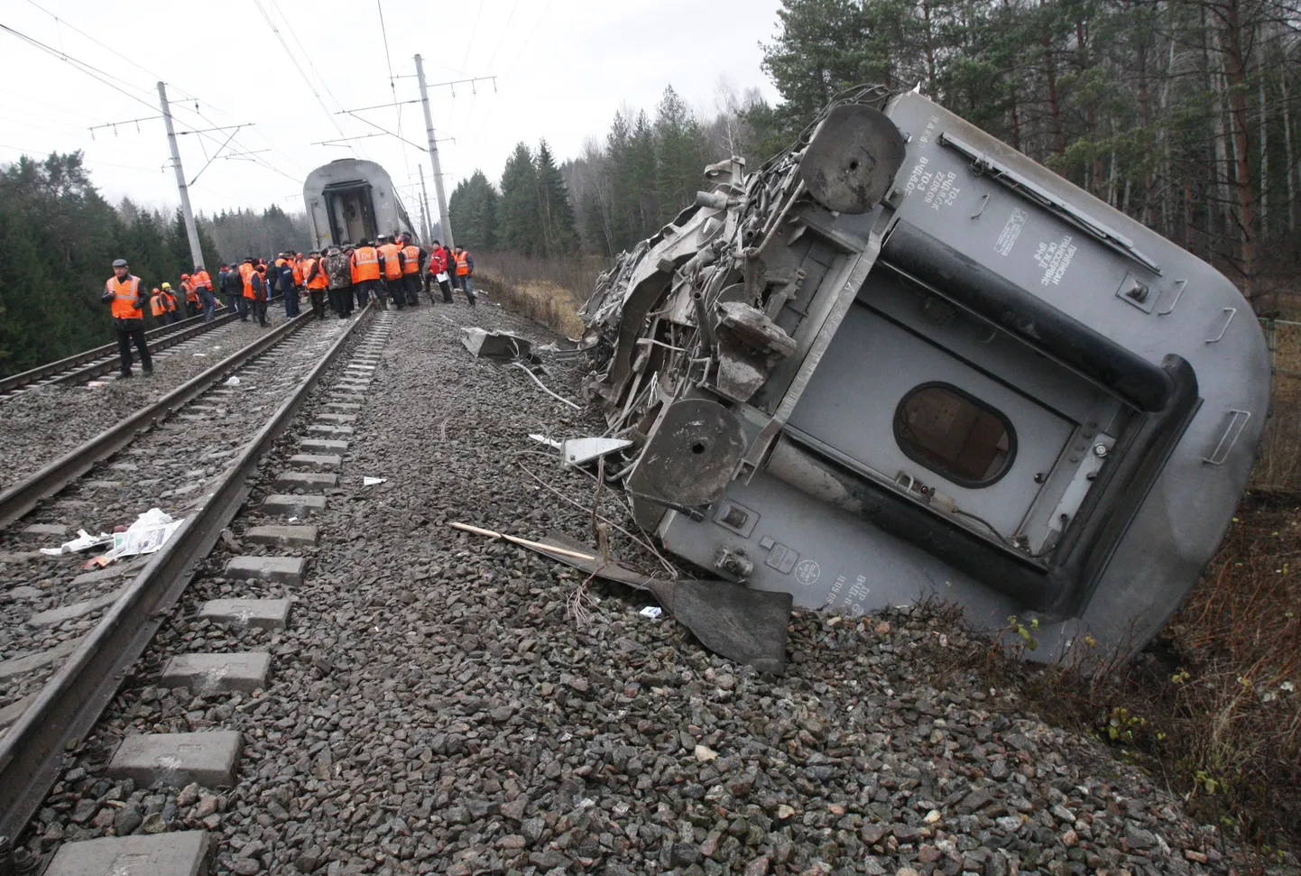 Railroad workers stand next to a damaged coach at the site of a train derailment near the town of Uglovka, some 400 km (250 miles) north-east of Moscow, Russia, Saturday, Nov. 28, 2009. An express train carrying hundreds of passengers from Moscow to St. Petersburg derailed, killing dozens of people and injuring scores of others in what may have been an act of sabotage, Russian officials said. (AP Photo/Ivan Sekretarev) / SCANPIX Code: 436