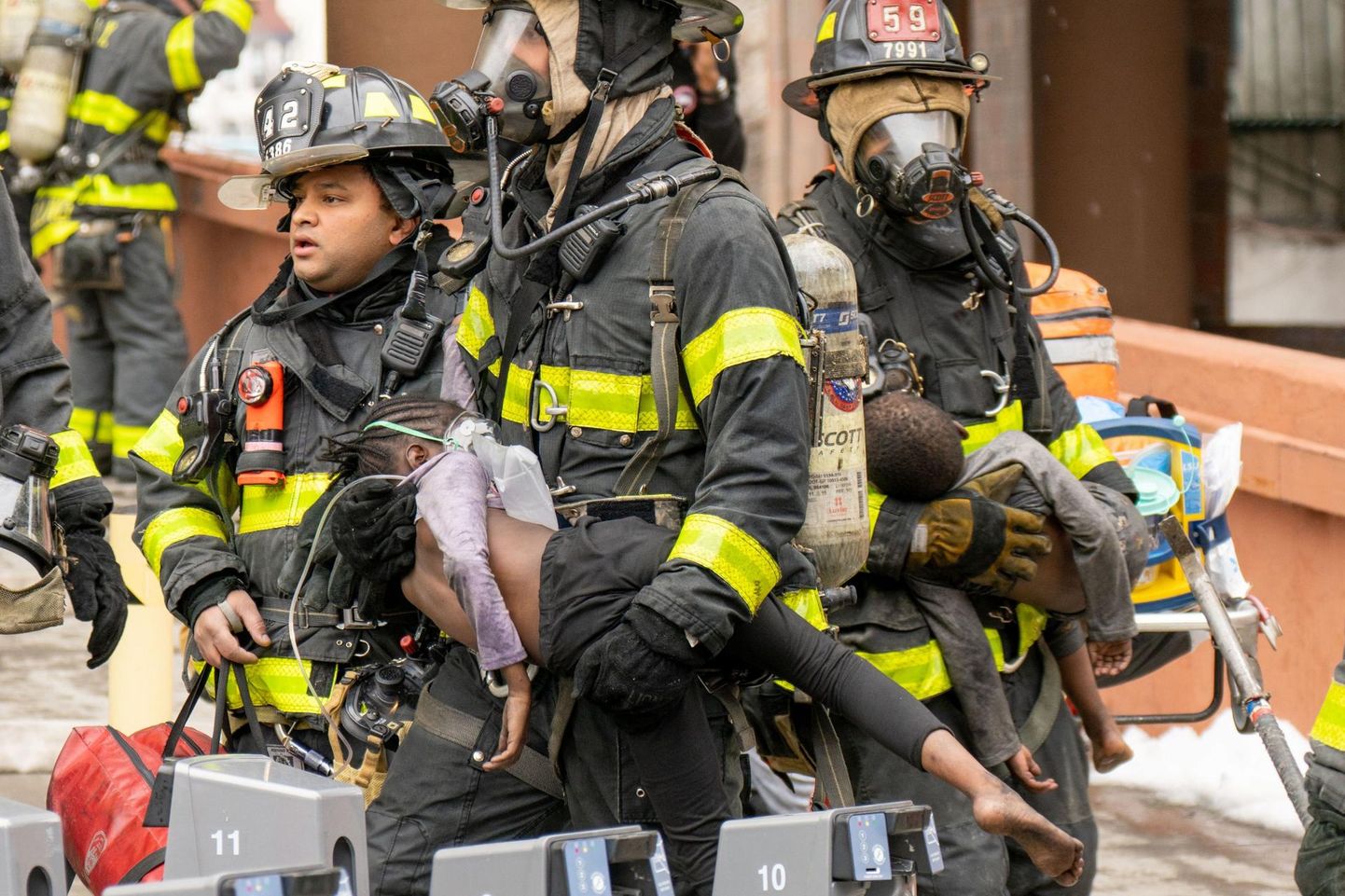 Tuletõrjujad kannavad pühapäeval New Yorgis Bronxi linnaosas kõrghoonest välja tulekahjusuitsus kannatada saanud lapsi. 