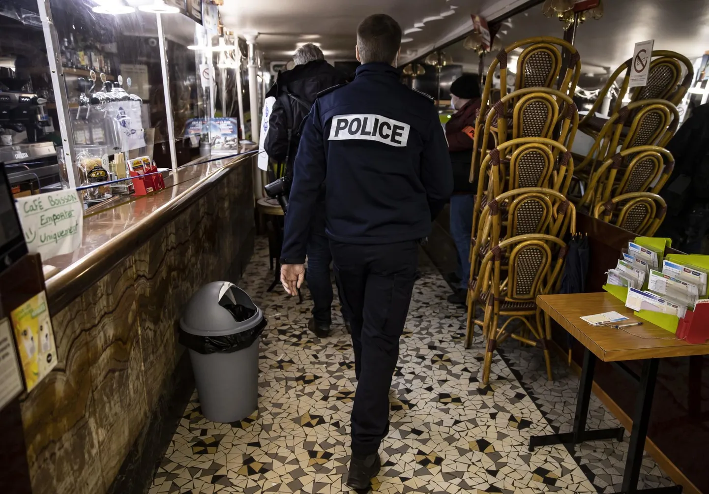 Prantsuse politseinik kontrollib koroonapiirangute täitmist baaris. 