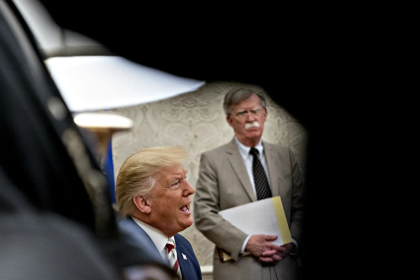 USA riikliku julgeoleku nõunik John Bolton (tagaplaanil) jälgib president Donald Trumpi kõnelemas 2019. aasta augustis.