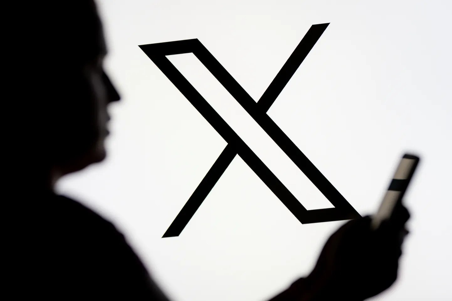 Inimene vaatab Xi logo taustal nutitelefoni.