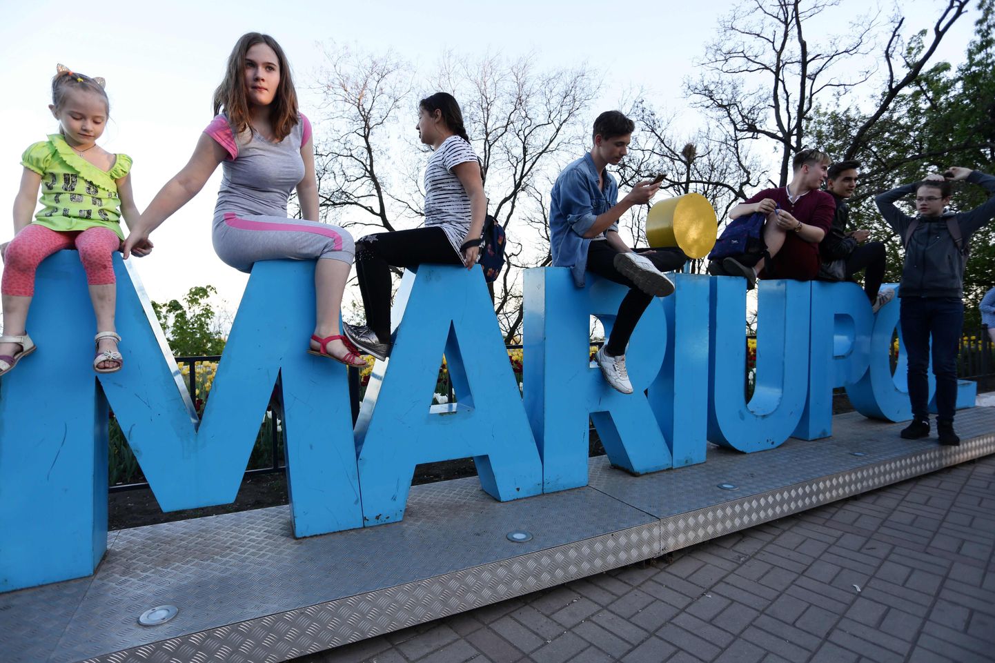 Inimesed Mariupoli linna sildil istumas.