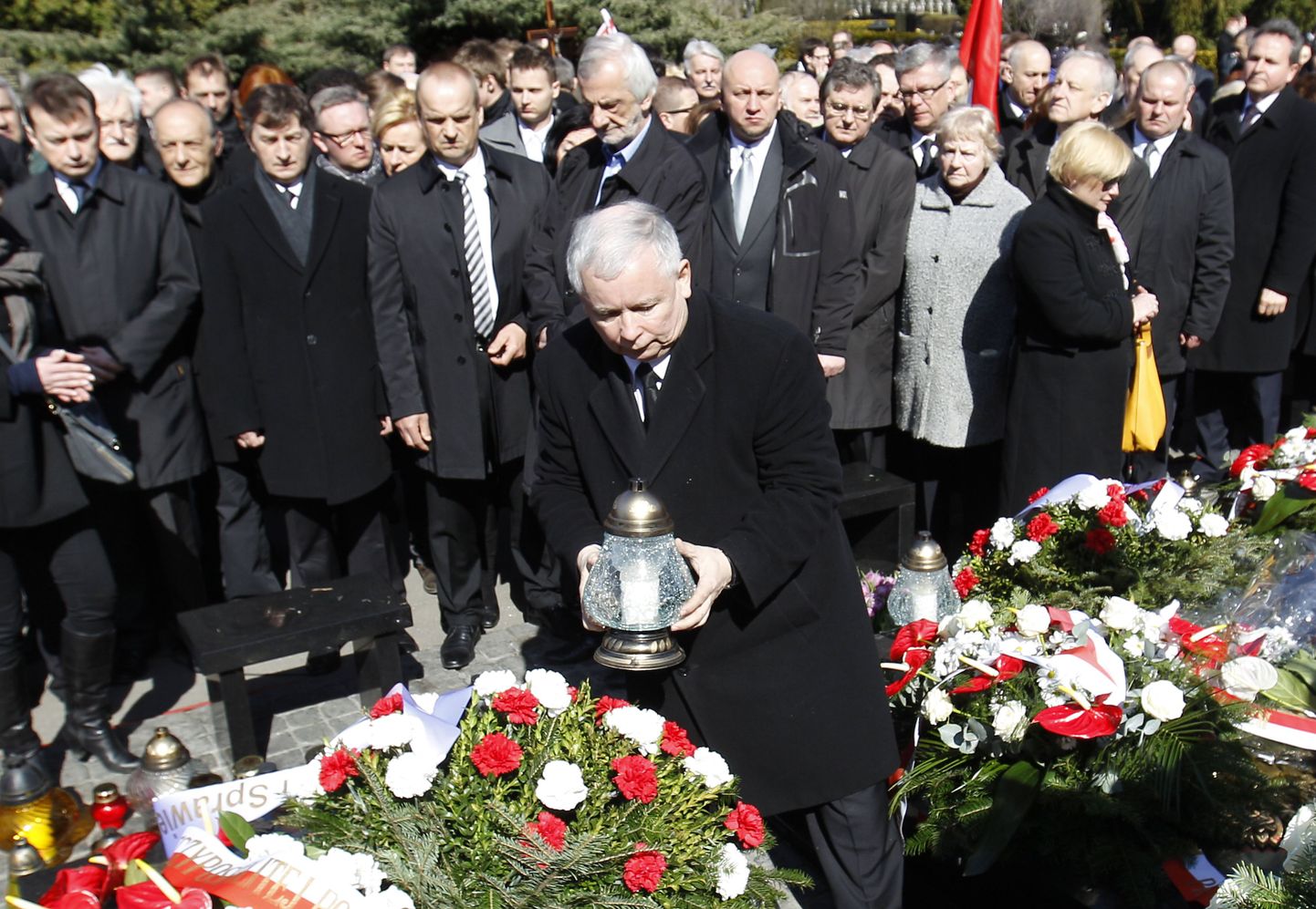 Jaroslaw Kaczyński (keskel) asetab Varssavi Powazki sõjaväekalmistul küünla Smolenski lennuõnnetuse ohvrite mälestuseks.